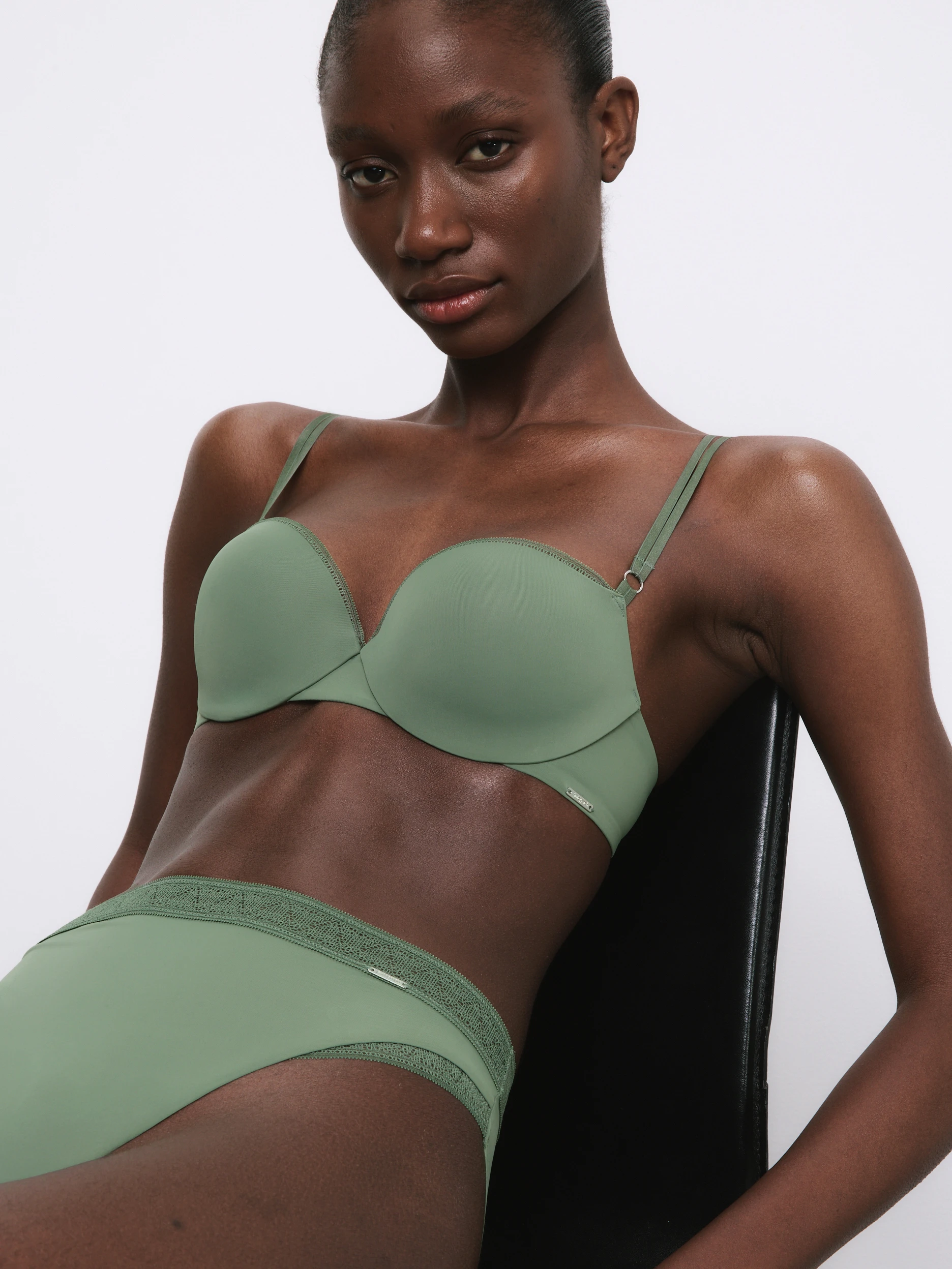 Woman wearing a green lingerie set sat on a chair