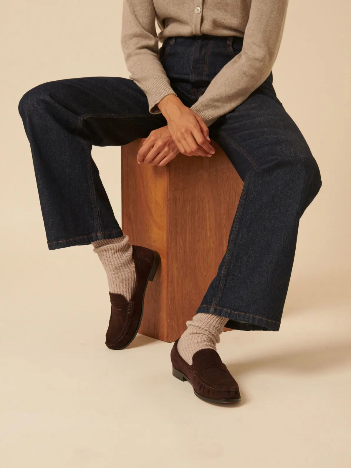 Woman wearing jeans, beige cardigan, ribbed beige socks and suede loafers