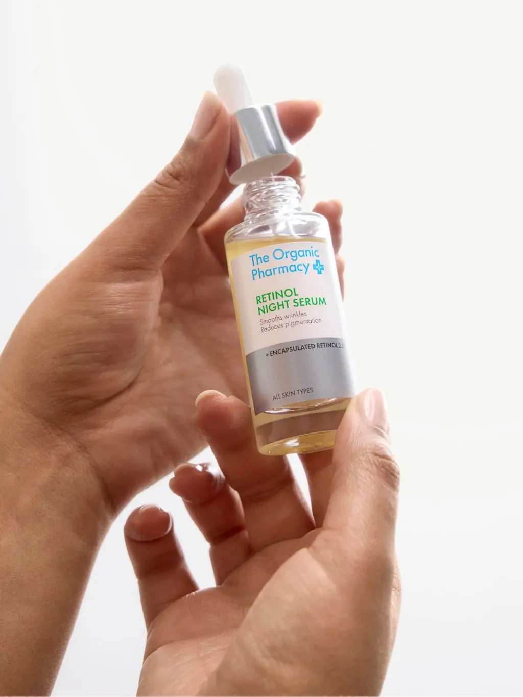 A close up of hands holding a bottle of retinol serum
