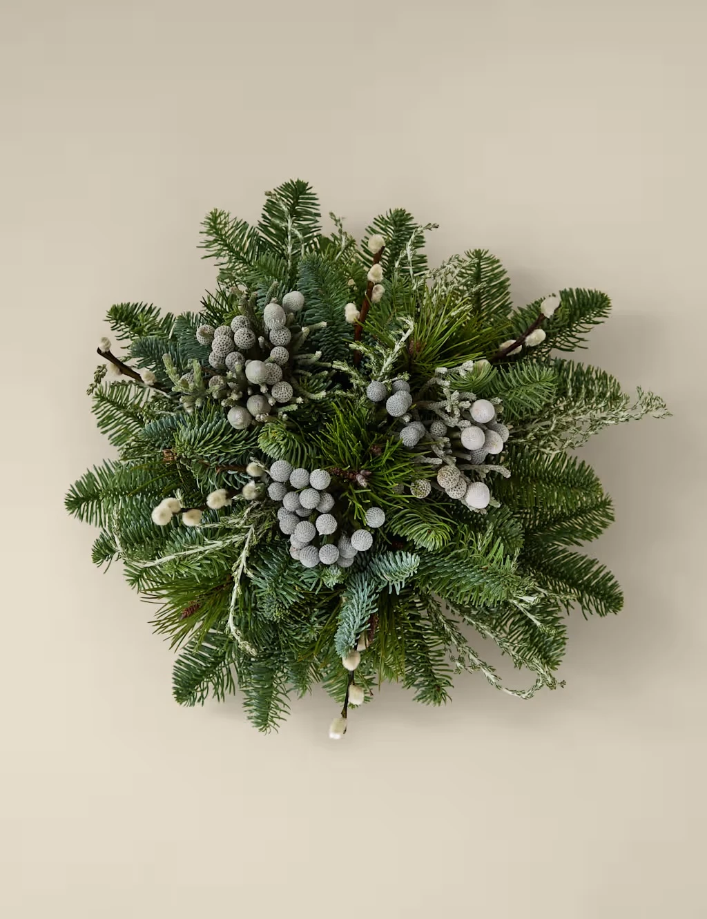 Green centrepiece made from winter foliage and neutral berries.