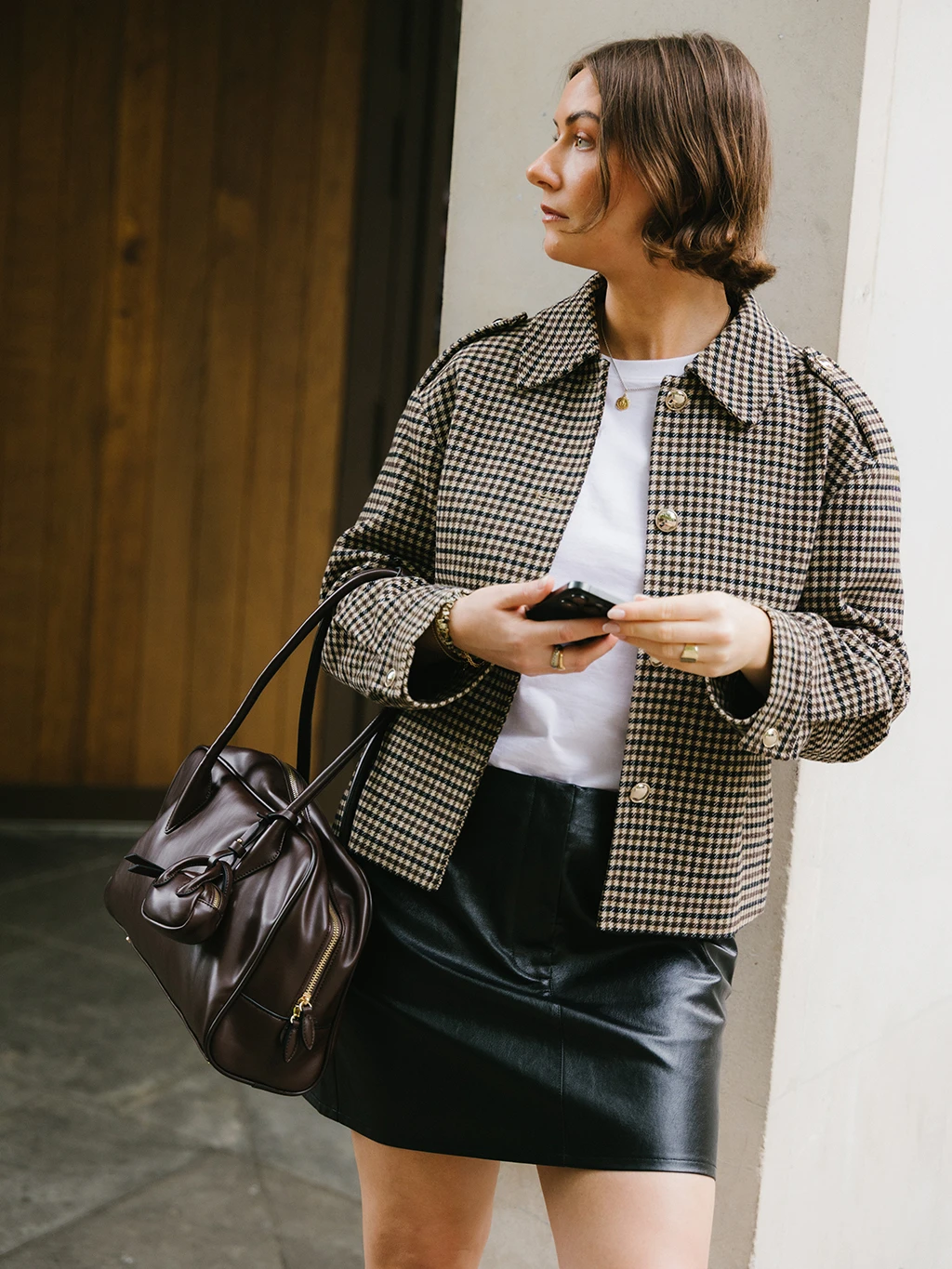 Sophie Watson wearing a checked jacket, black mini skirt and brown handbag