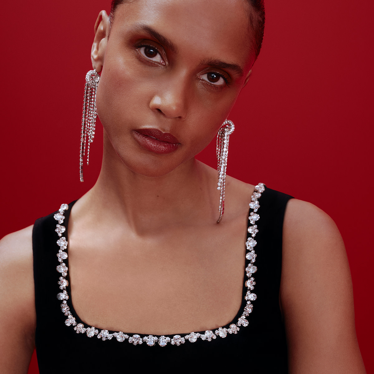 Woman wearing chandelier earrings and a black embellished dress