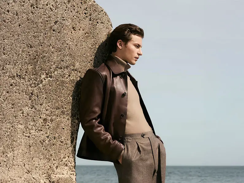 Man wearing a brown leather Harrington jacket with a camel roll-neck jumper and tailored trousers