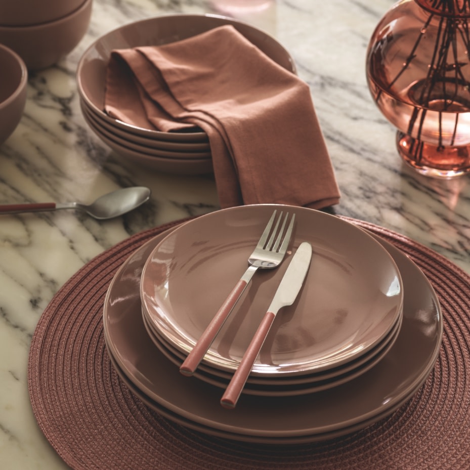 Stack of pink dinner plates on pink placemat. Shop tableware