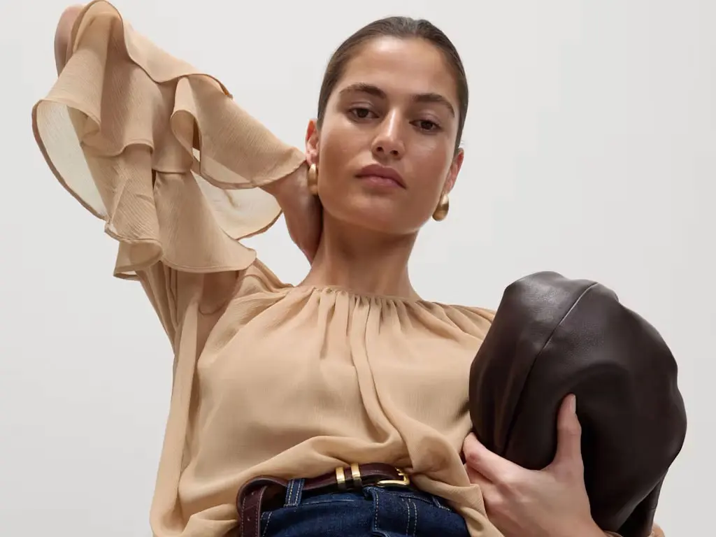 Woman wearing dark cream frilled blouse. 