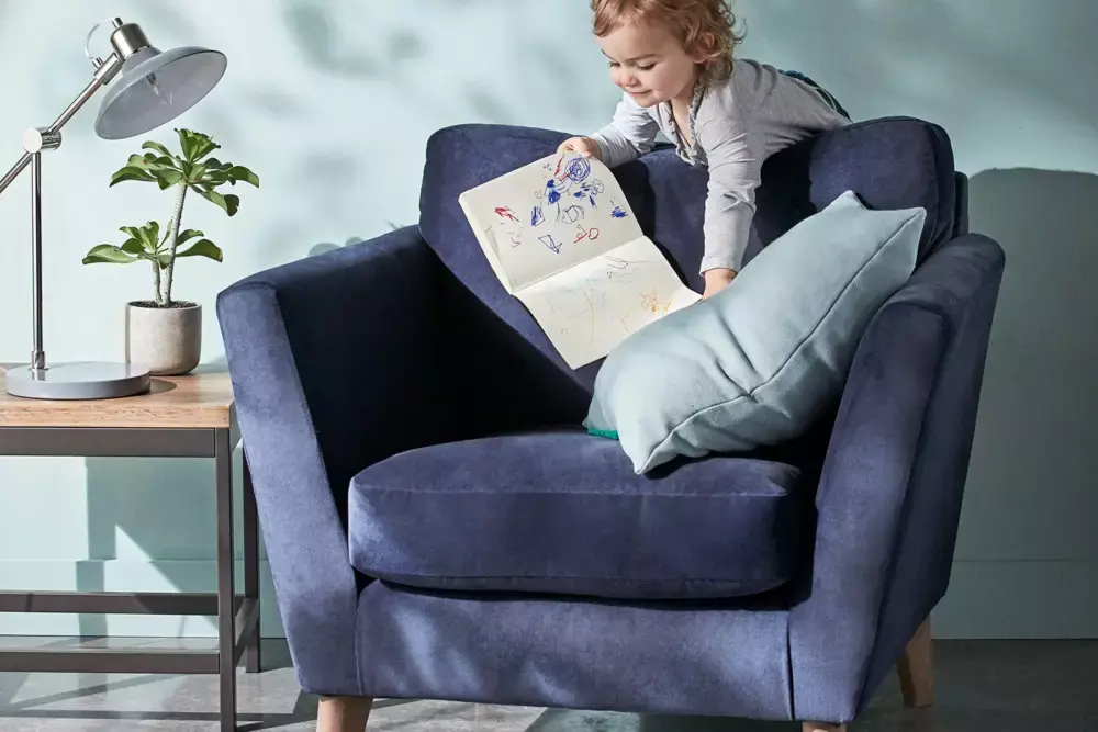 Child playing on a blue armchair. Shop sofas
