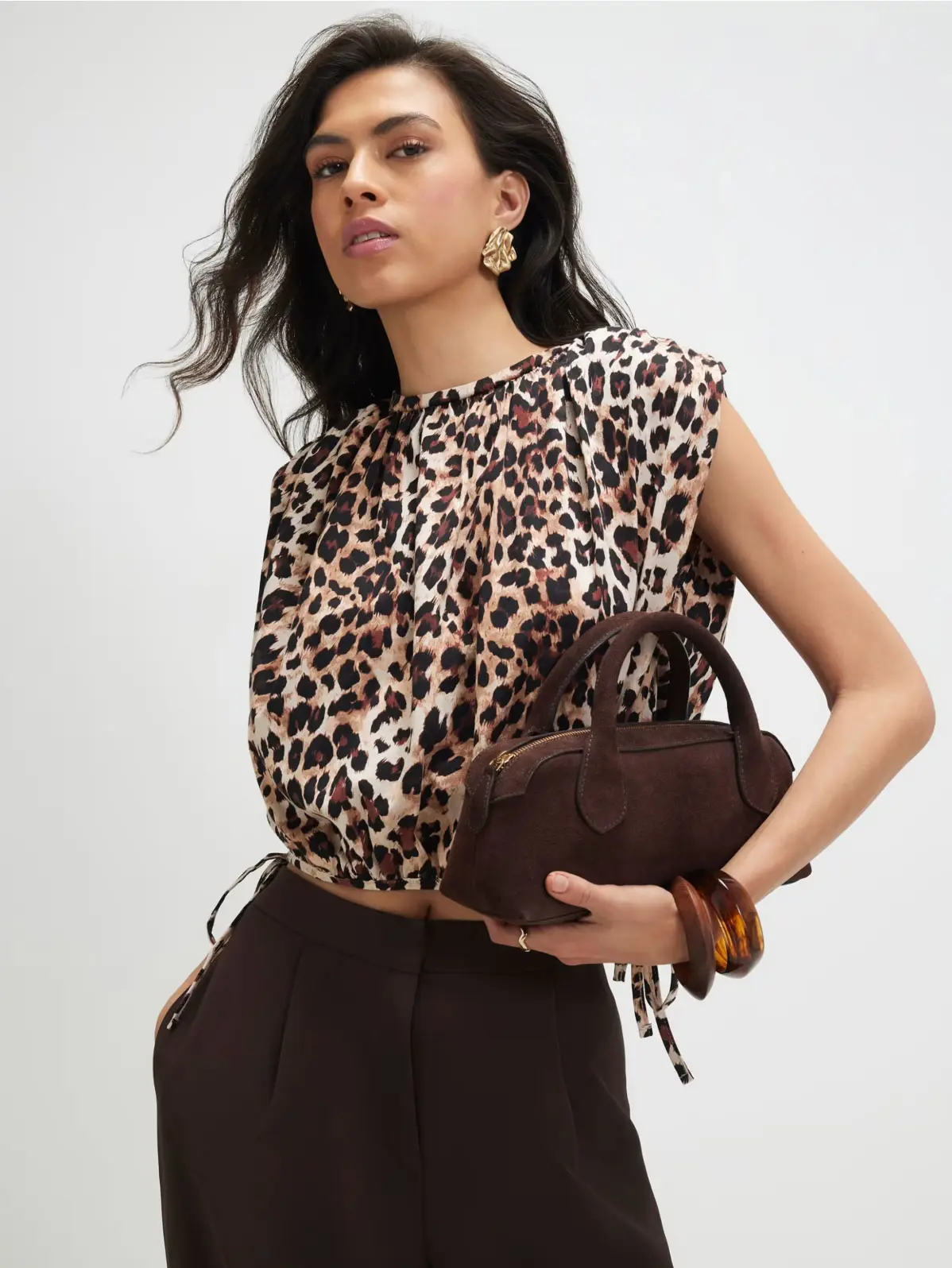 Woman wearing animal-print top and chocolate brown trousers