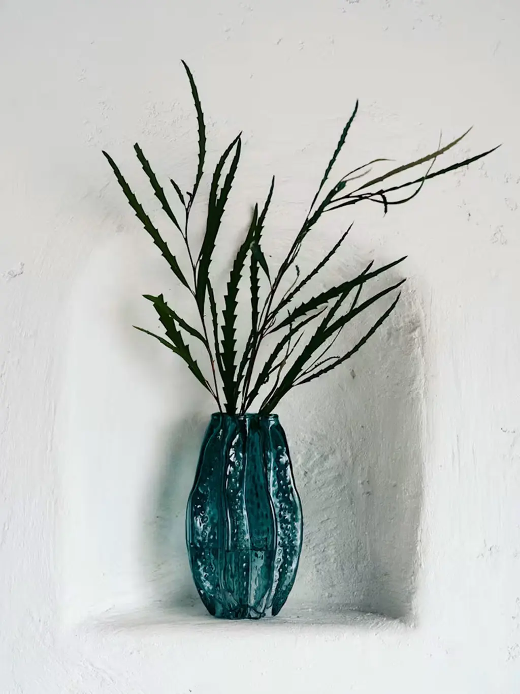 Blue glass vase with branches in it