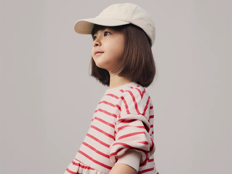 Girl wearing cream cap and red and white striped dress
