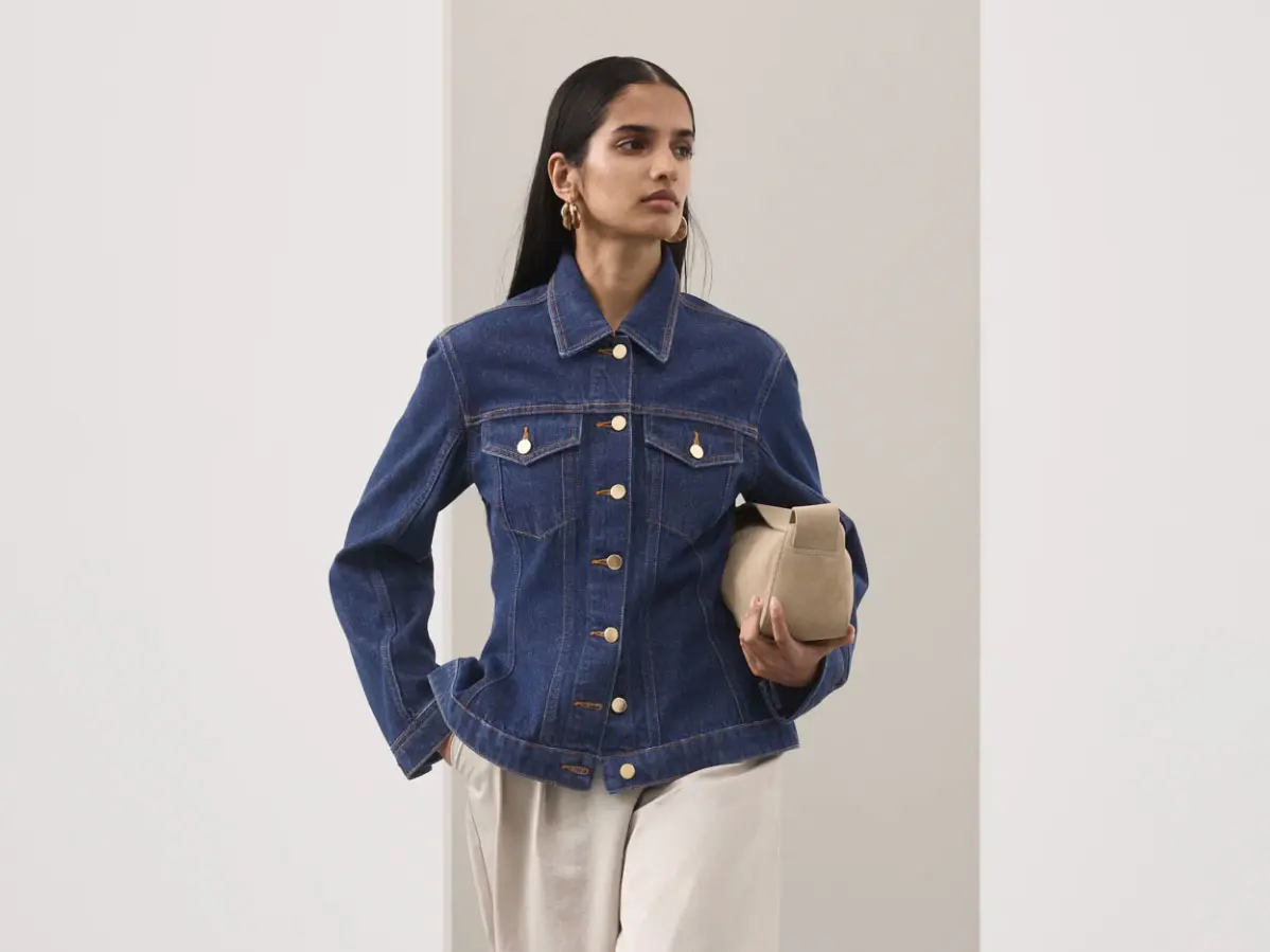 Woman wearing denim jacket with smart trousers and clutch bag