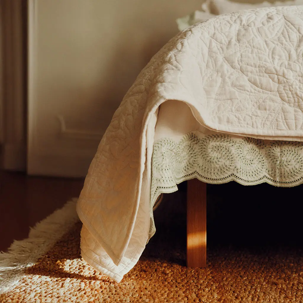 Bed with neutral bedding against a neutral backdrop
