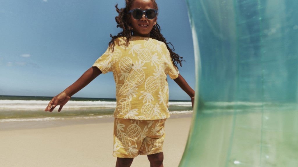 Boy wearing a yellow and white pineapple print t-shirt and matching shorts. Visit The Holiday Shop
