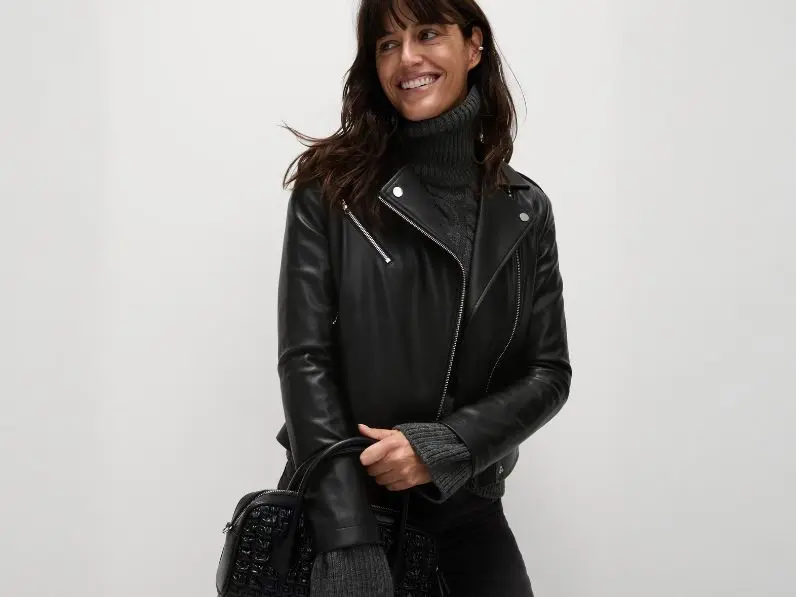 A woman wears a biker jacket over a polo neck