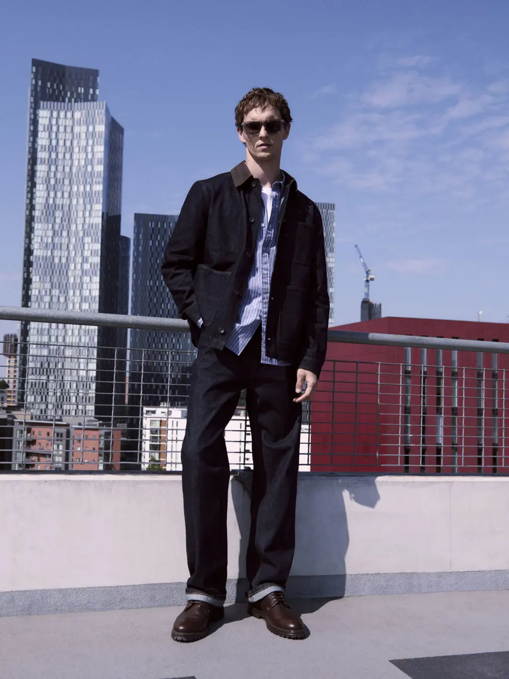 Man wearing dark indigo jeans, a blue shirt and navy jacket