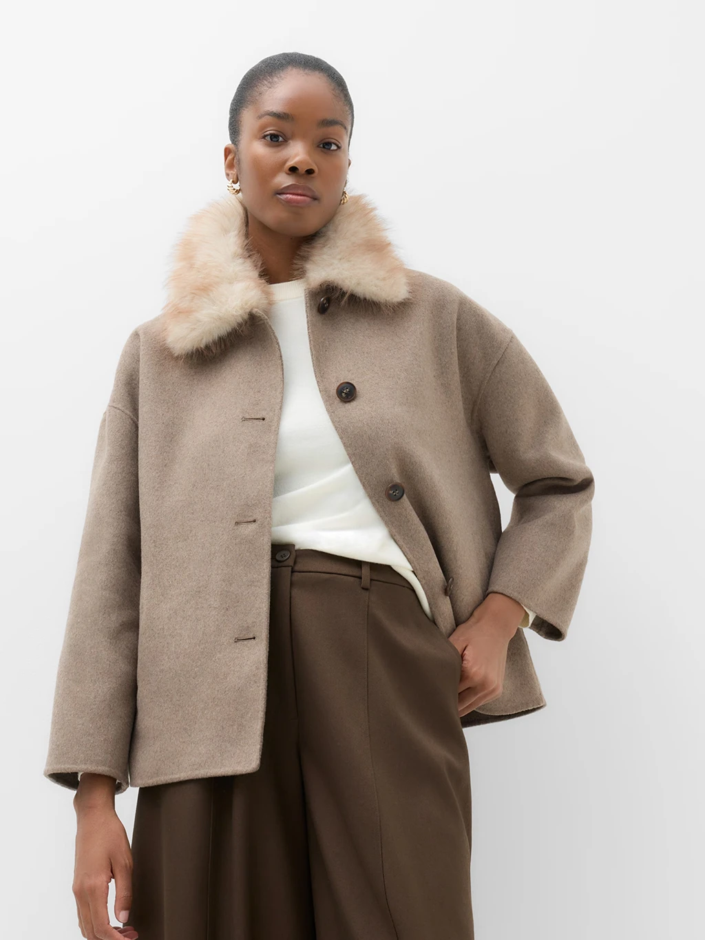 Model wearing a neutral beige wool-blend coat with a faux fur collar and buttons up the front.