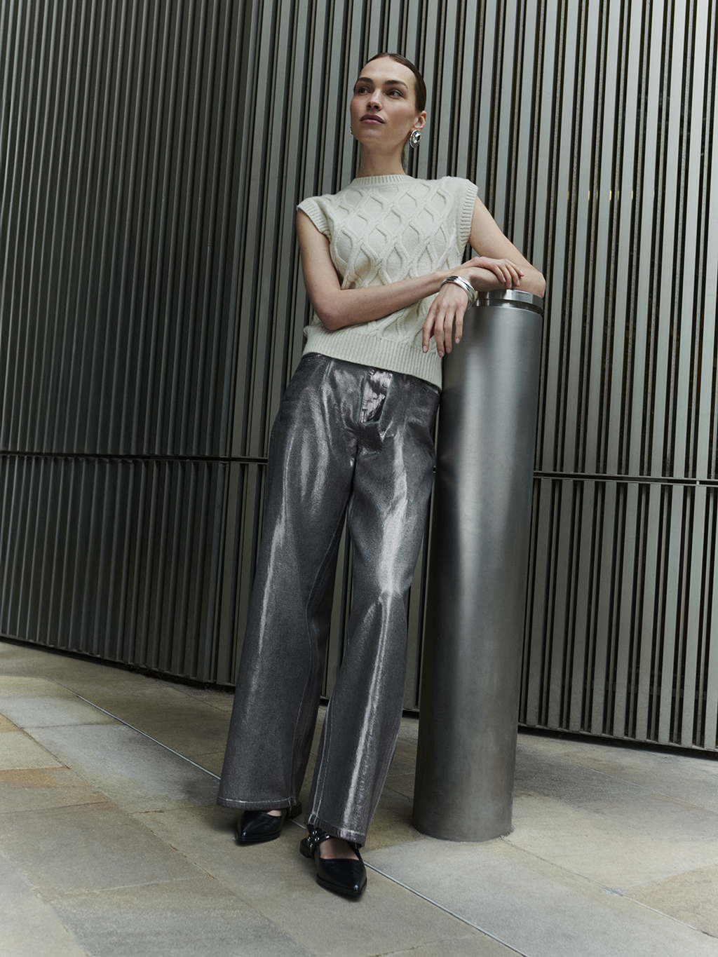 Woman wearing sleeveless sweater and silver jeans