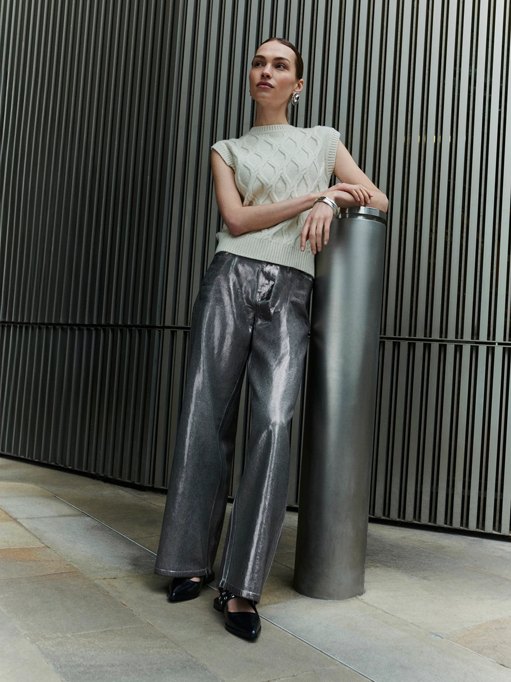 Woman wearing sleeveless sweater and silver jeans