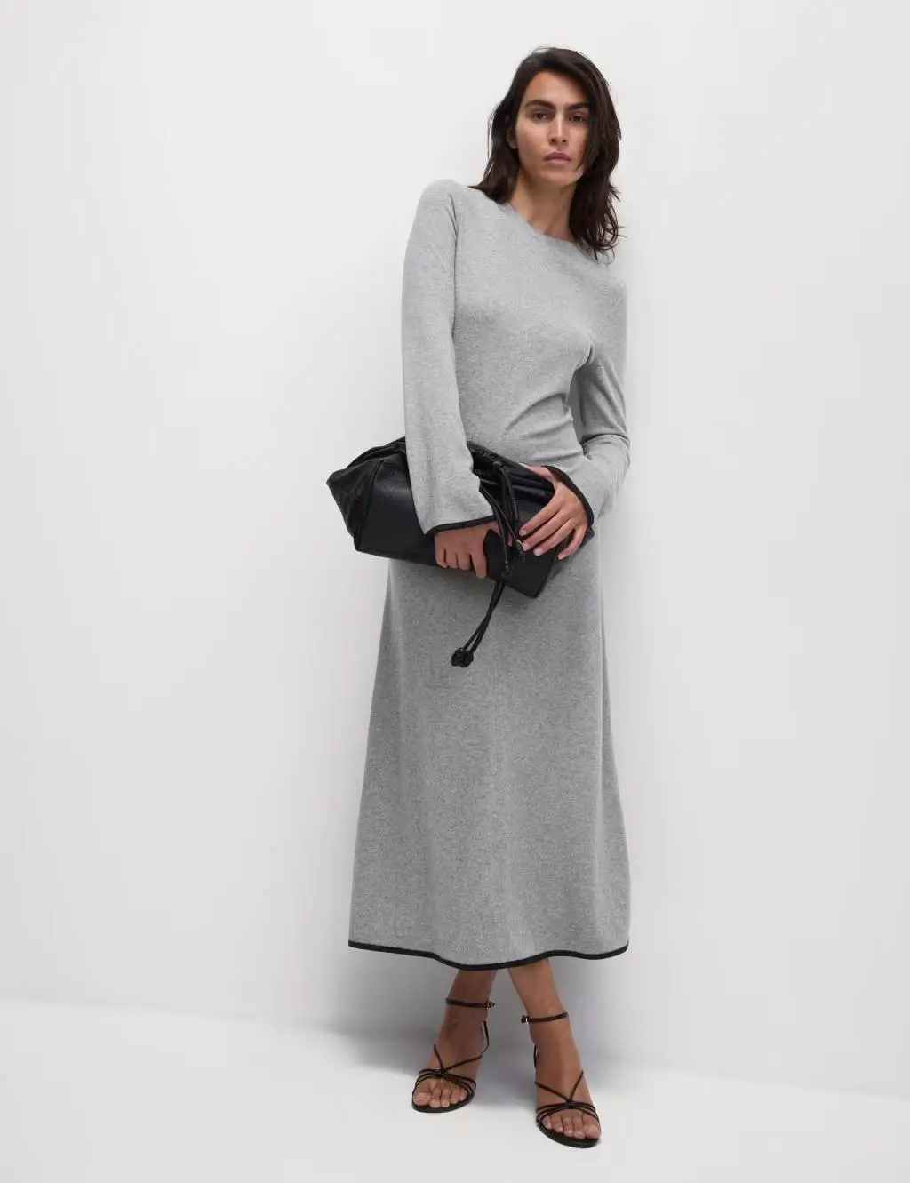 Woman wearing grey column dress and holding a black handbag