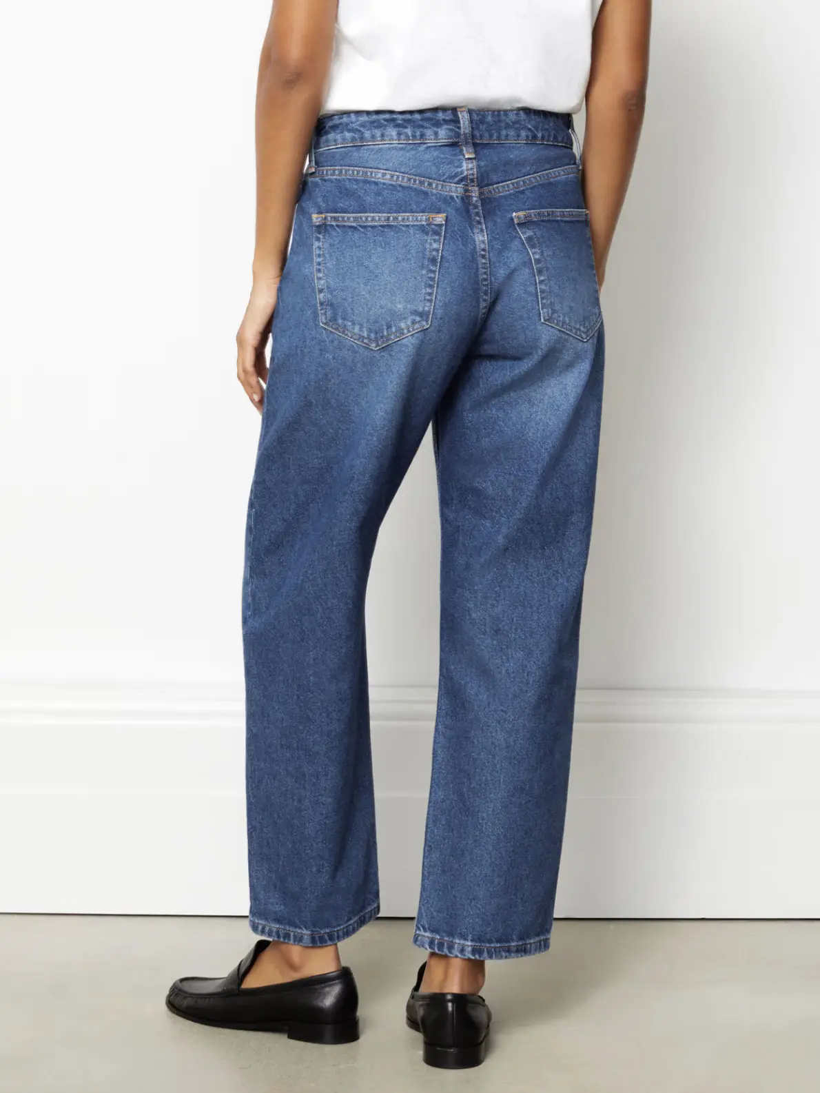 Woman wearing blue jeans with white T-shirt and black loafers