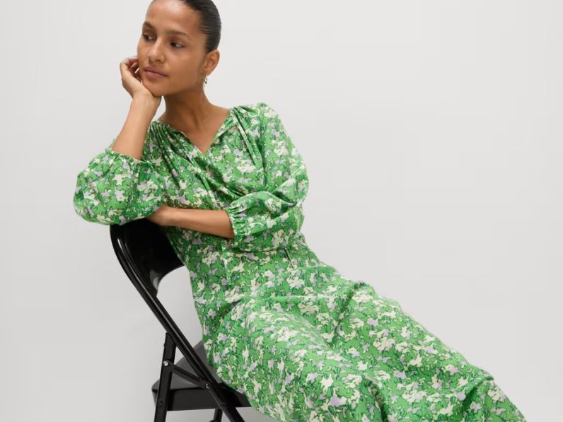 A woman sat on a chair wearing a green floral dress