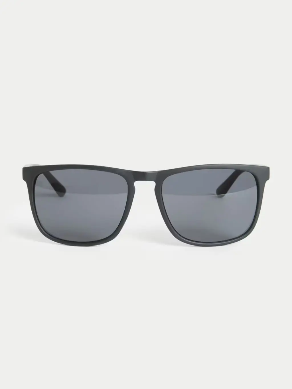 A cut out of black framed sunglasses shot against a light grey background