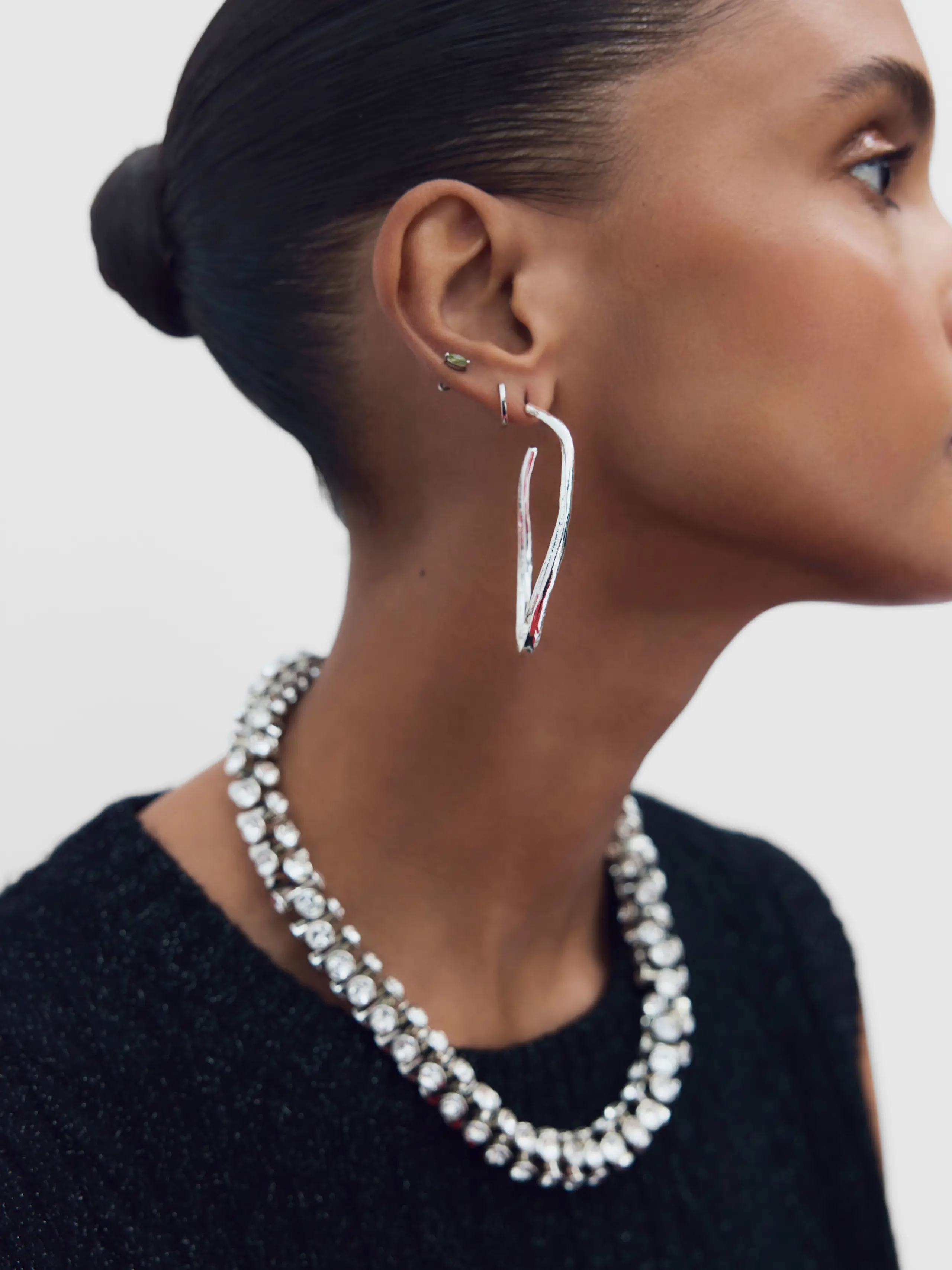 Woman wearing silver sculptural earrings and silver necklace