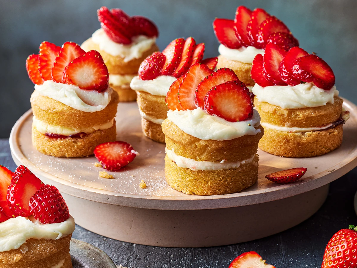 A plate of mini Victoria sponge cakes with strawberries on top