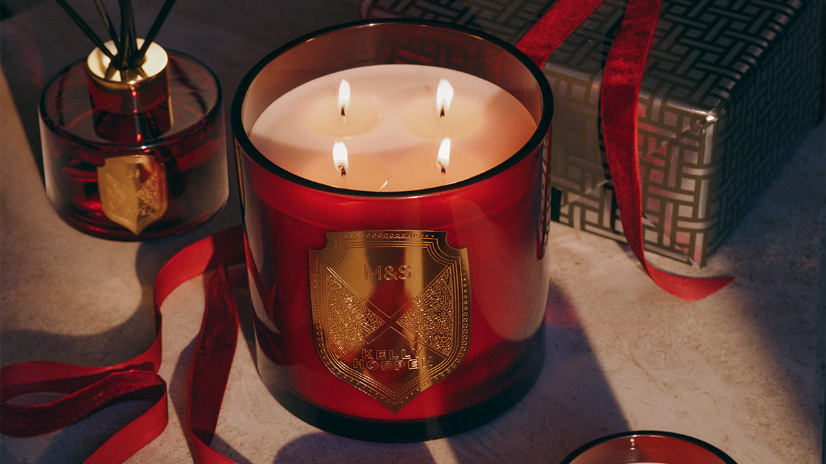 Four-wick candle in red glass jar with gold crest design