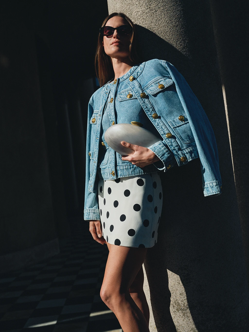 Woman wearing layered denim jackets with a polka dot skirt