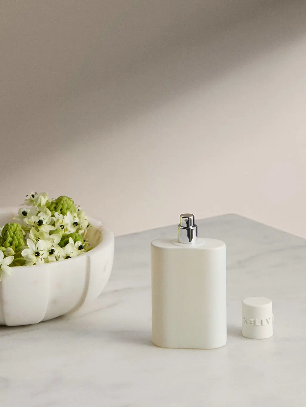 Room spray beside a bowl of flowers