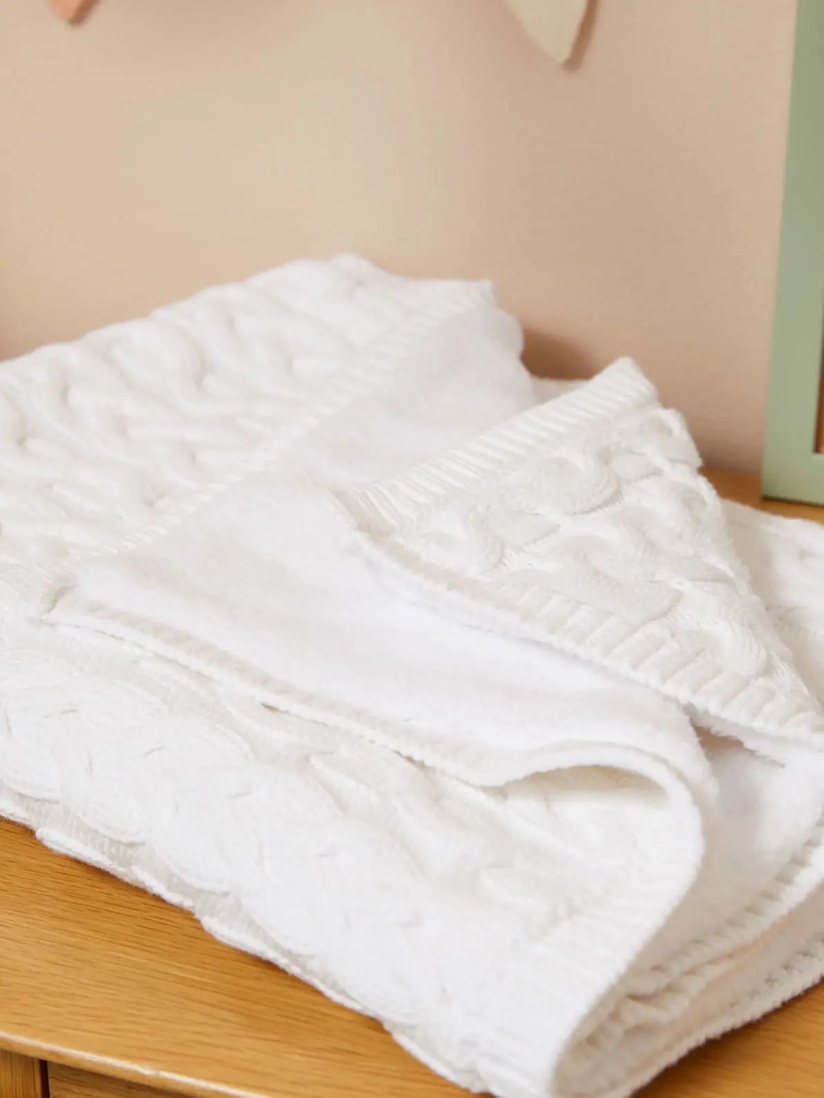 White cable-knitted shawl folded on a table