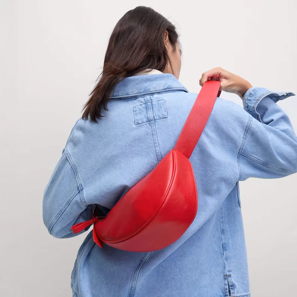 Woman wearing denim jacket and red faux-leather cross-body sling bag