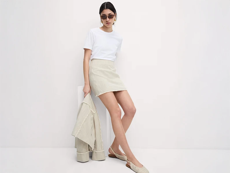 Woman wearing white T-shirt, beige mini skirt and beige pointed shoes
