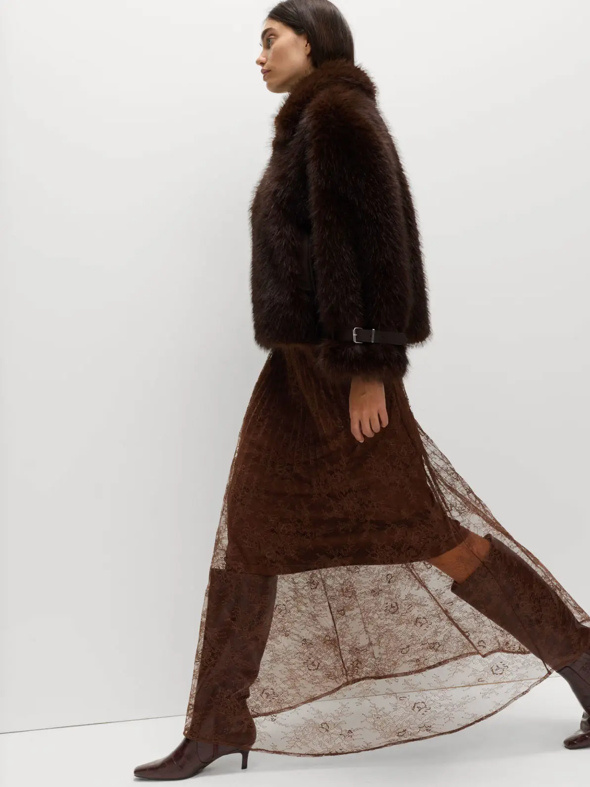 Woman wearing brown faux-fur jacket over lace skirt and tall heeled boots