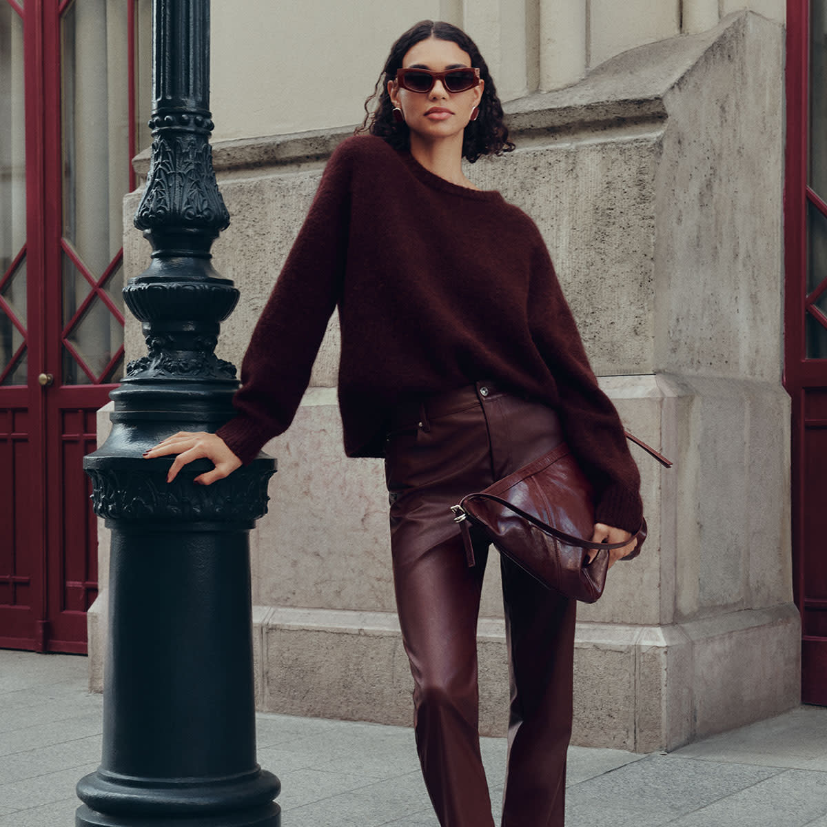 Woman wearing a burgundy jumper and faux leather trousers