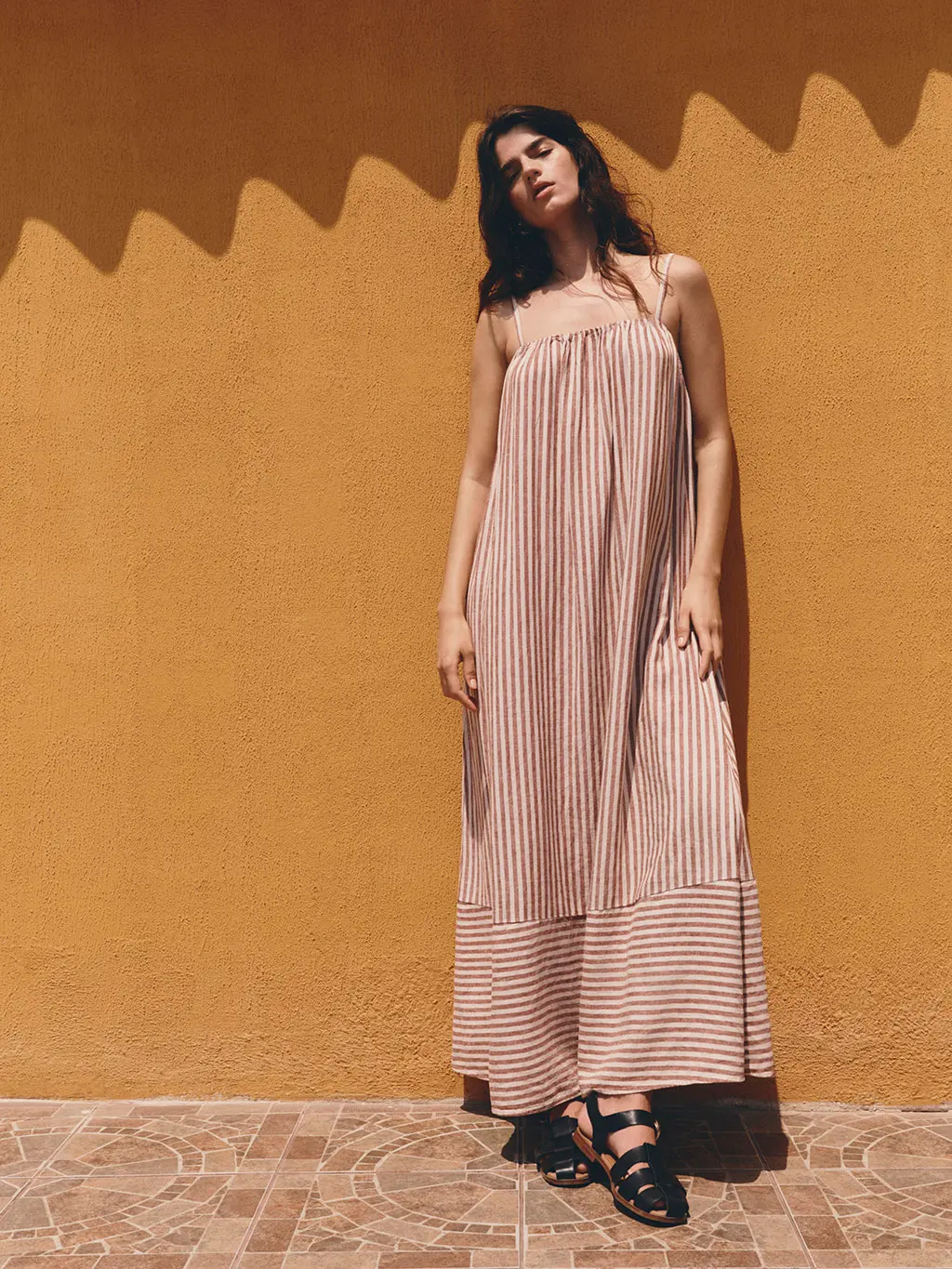 Woman in striped dress against yellow wall