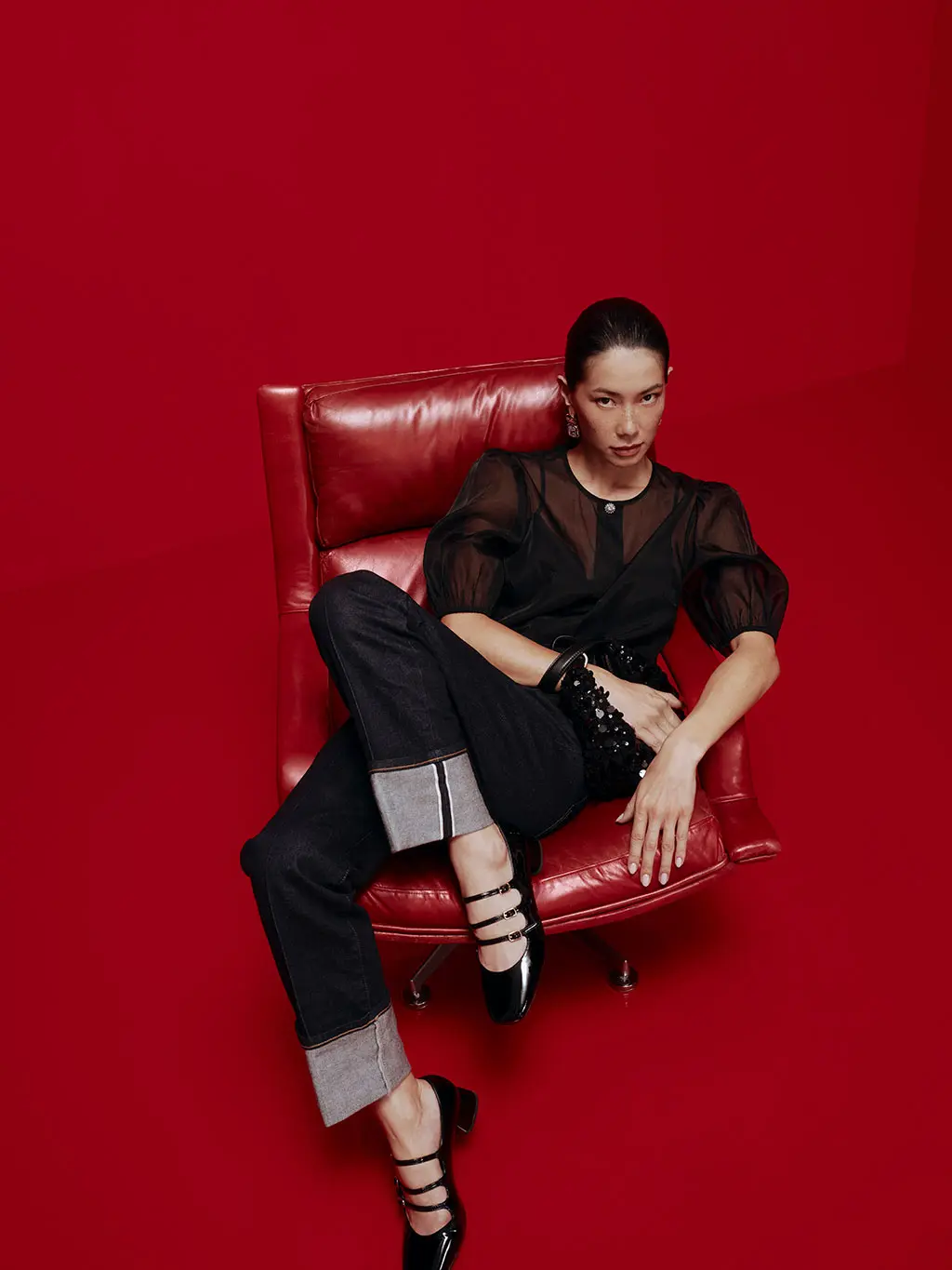 Woman wearing black sheer blouse, cuffed jeans and black strappy pumps