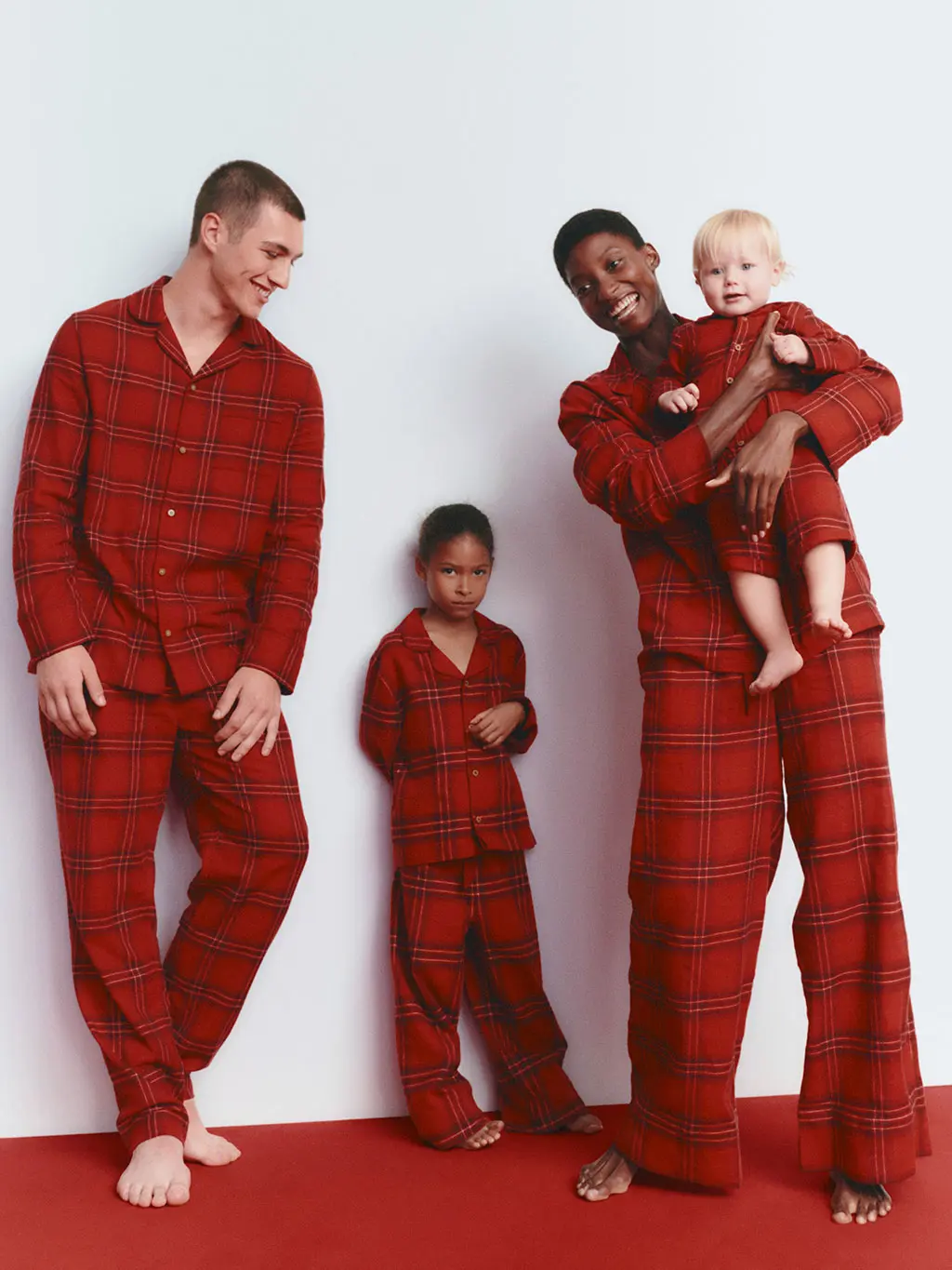 Two adults and two children wearing matching red flannel pyjamas.