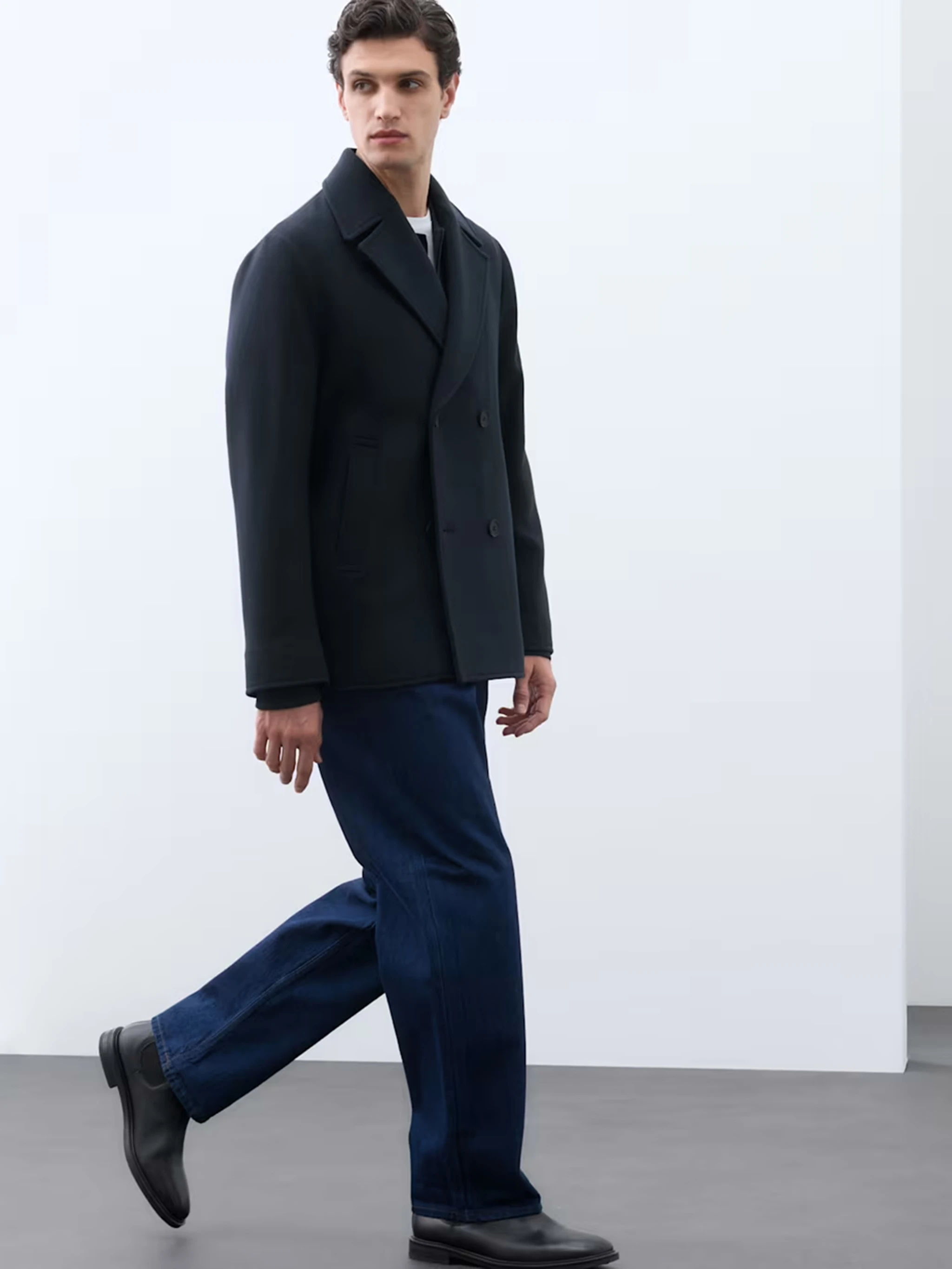 Man wearing smart navy trousers and a wool blend peacoat.