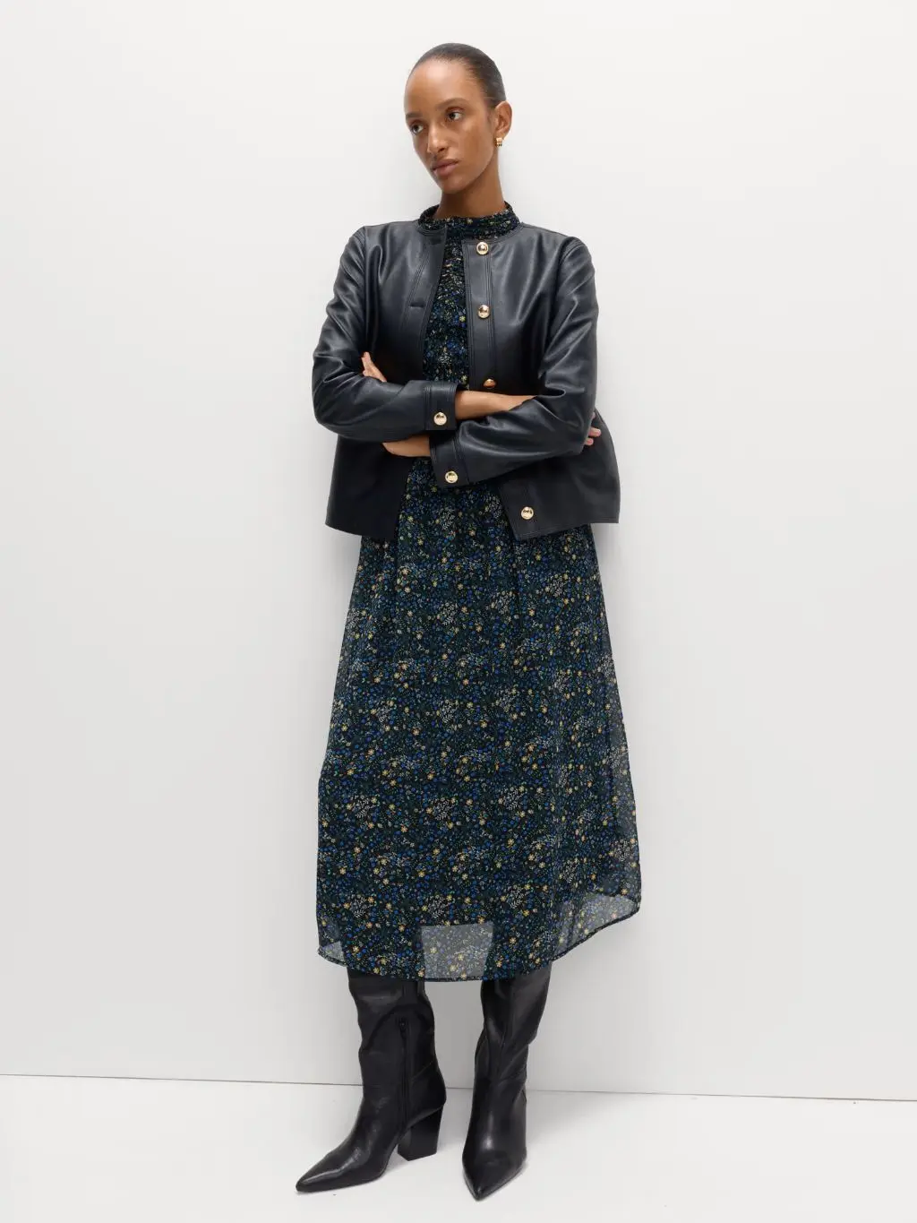 A woman wears a cropped leather jacket over a floral midi dress