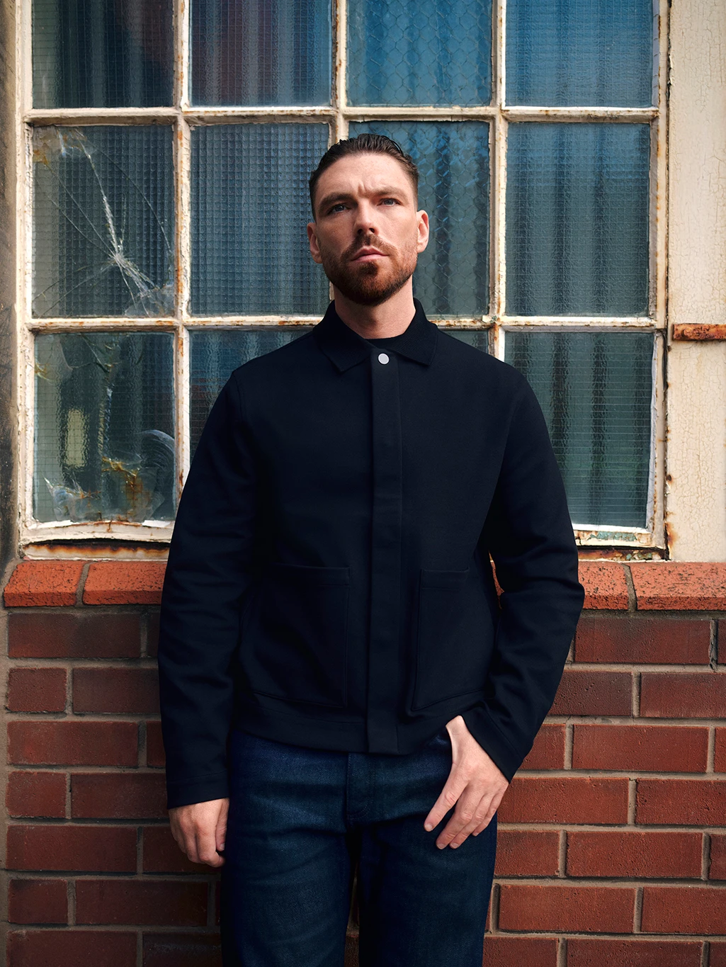 James Nelson Joyce wearing a navy jacket and jeans by Autograph