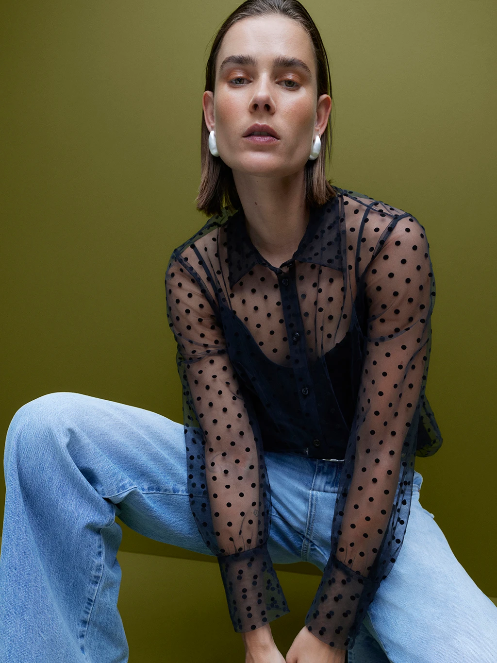 Woman wearing black sheer polka-dot blouse