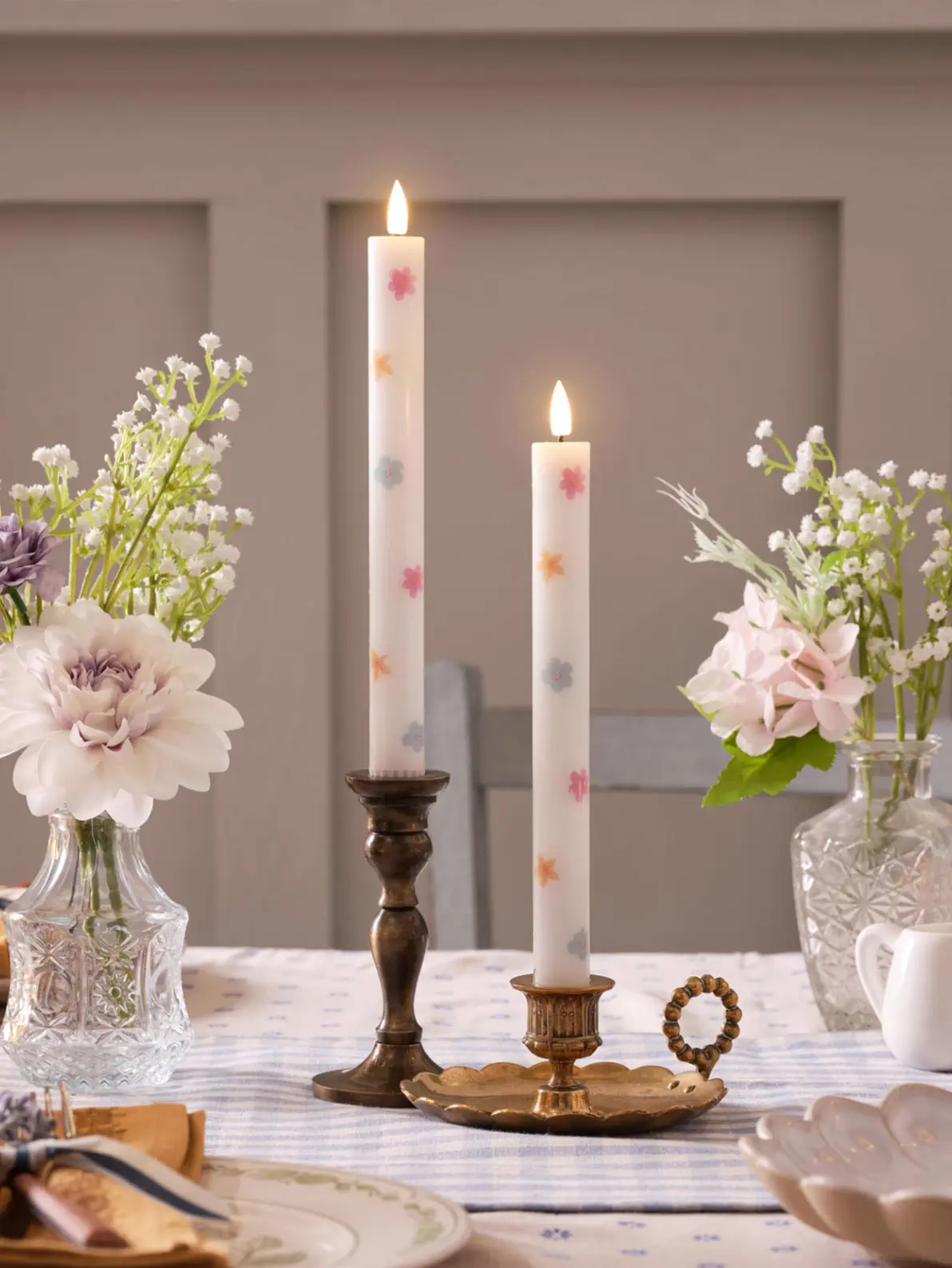 Set of two floral candlesticks placed in brass candle holders