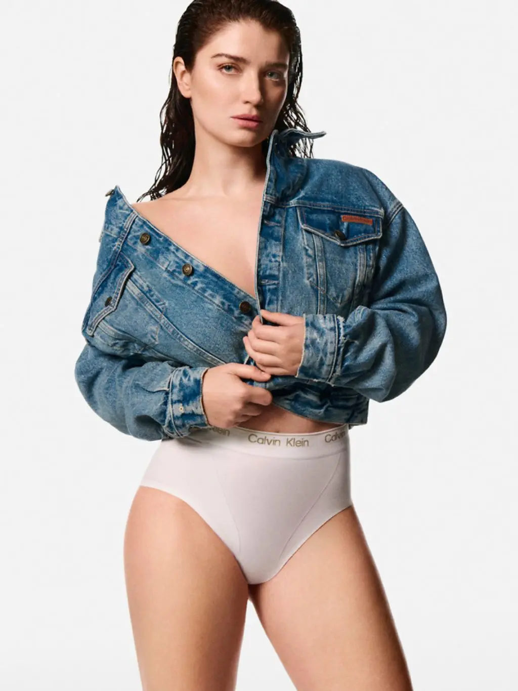 A woman wears white Calvin Klein shaping pants and a denim jacket