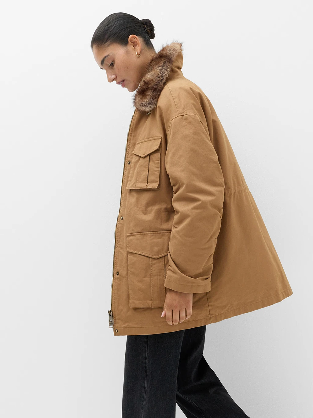 Model in a brown parka coat with a faux fur collar.