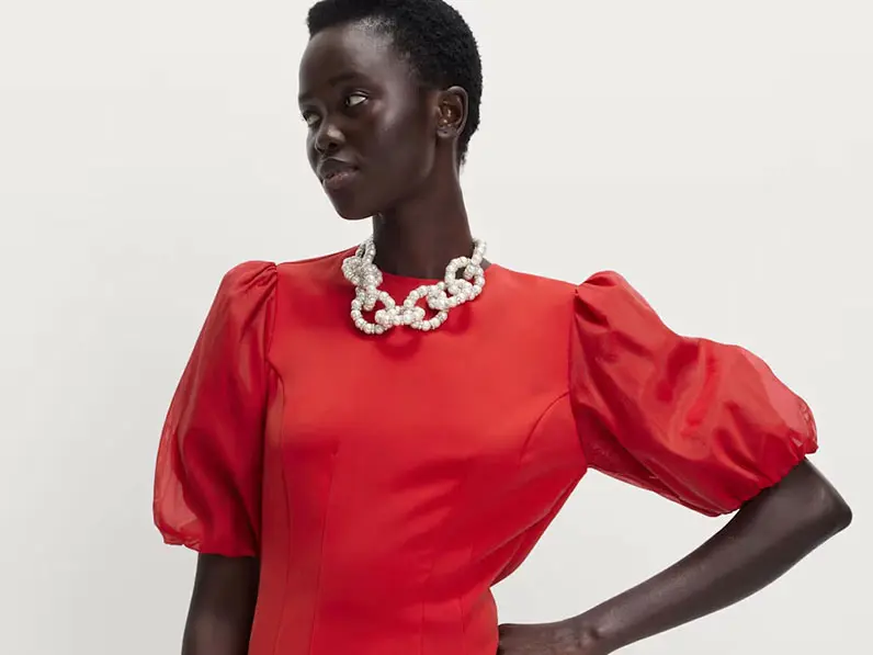 Woman in red dress with puff sleeves and pearl necklace