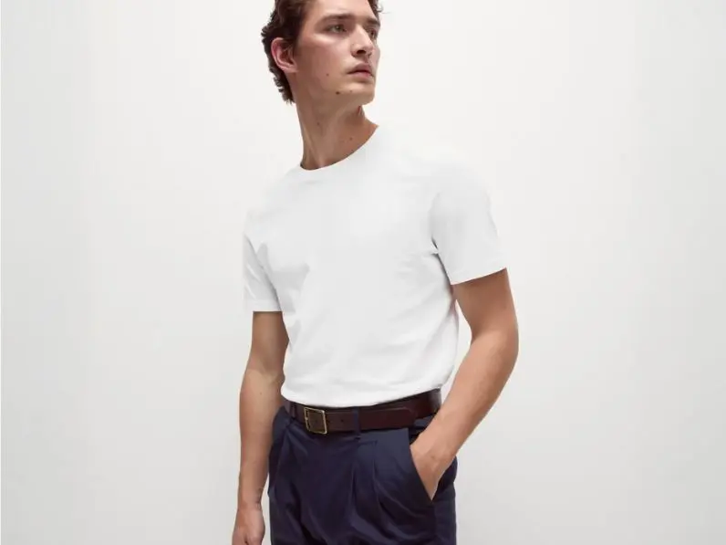 A man wears a white regular-fit T-shirt tucked into trousers