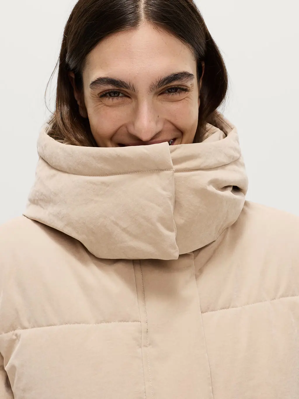 Woman wearing a beige hooded puffer jacket