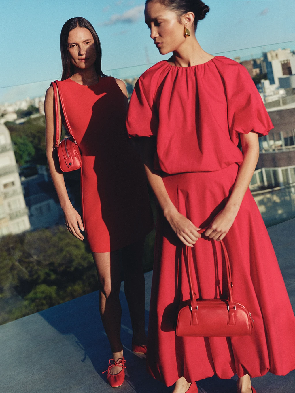 Two women wearing red going-out dresses with red handbags