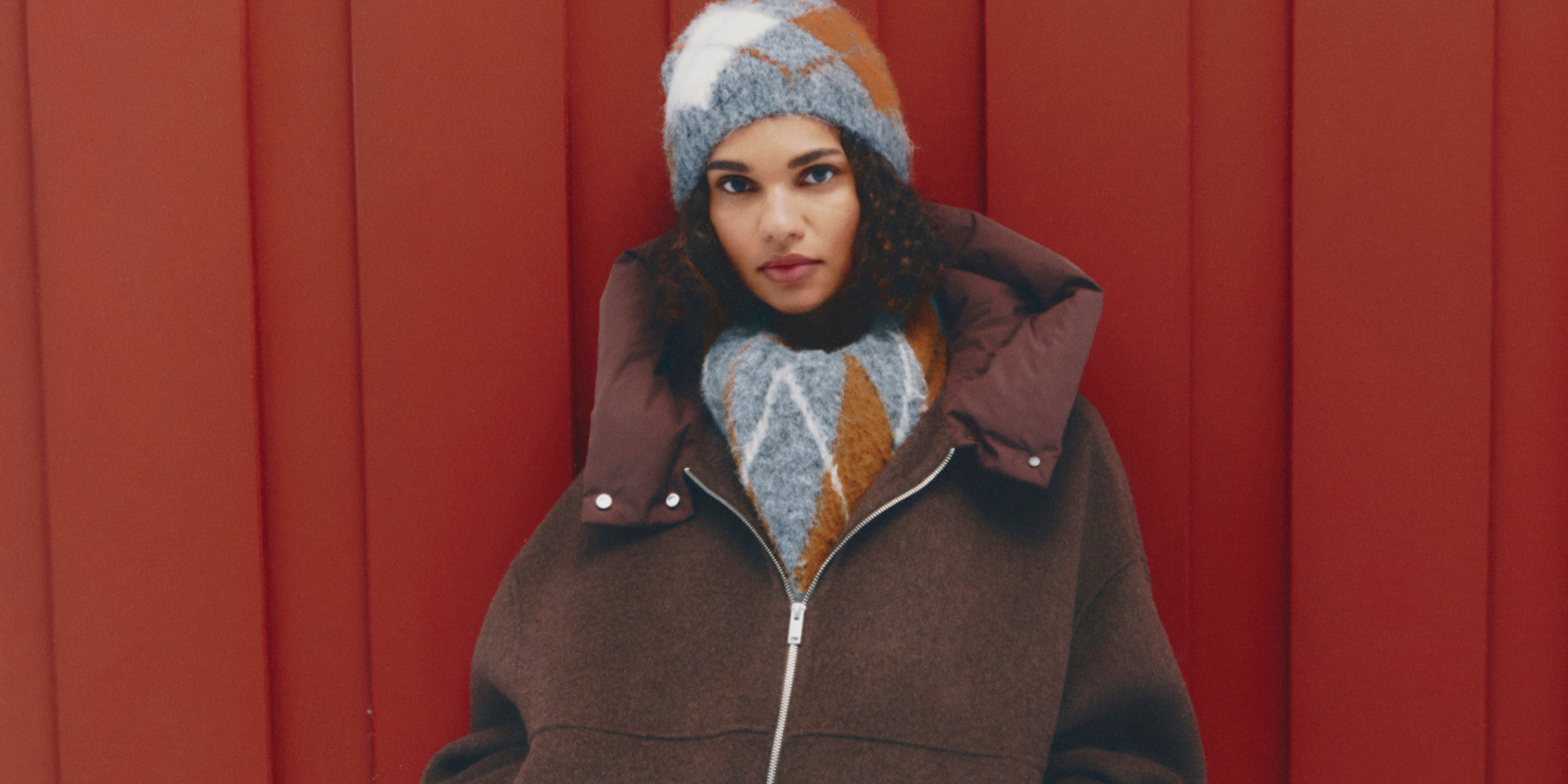 Woman wearing argyle hat and jumper with a brown hooded jacket